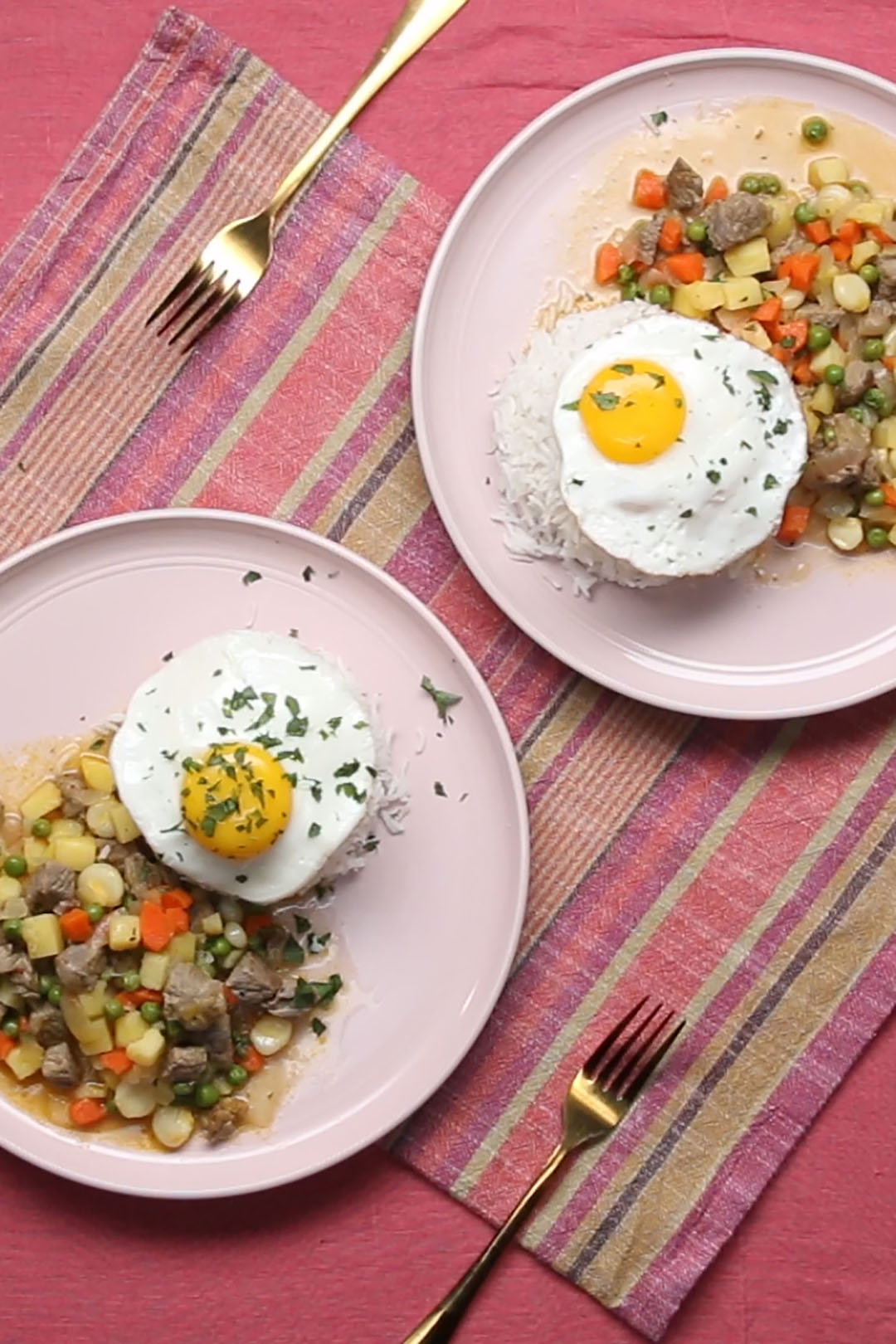 two plates of meat, veggies, potatoes, and a mound of rice topped with a sunny side up egg two plates of meat, veggies, potatoes, and a mound of rice topped with a sunny side up egg