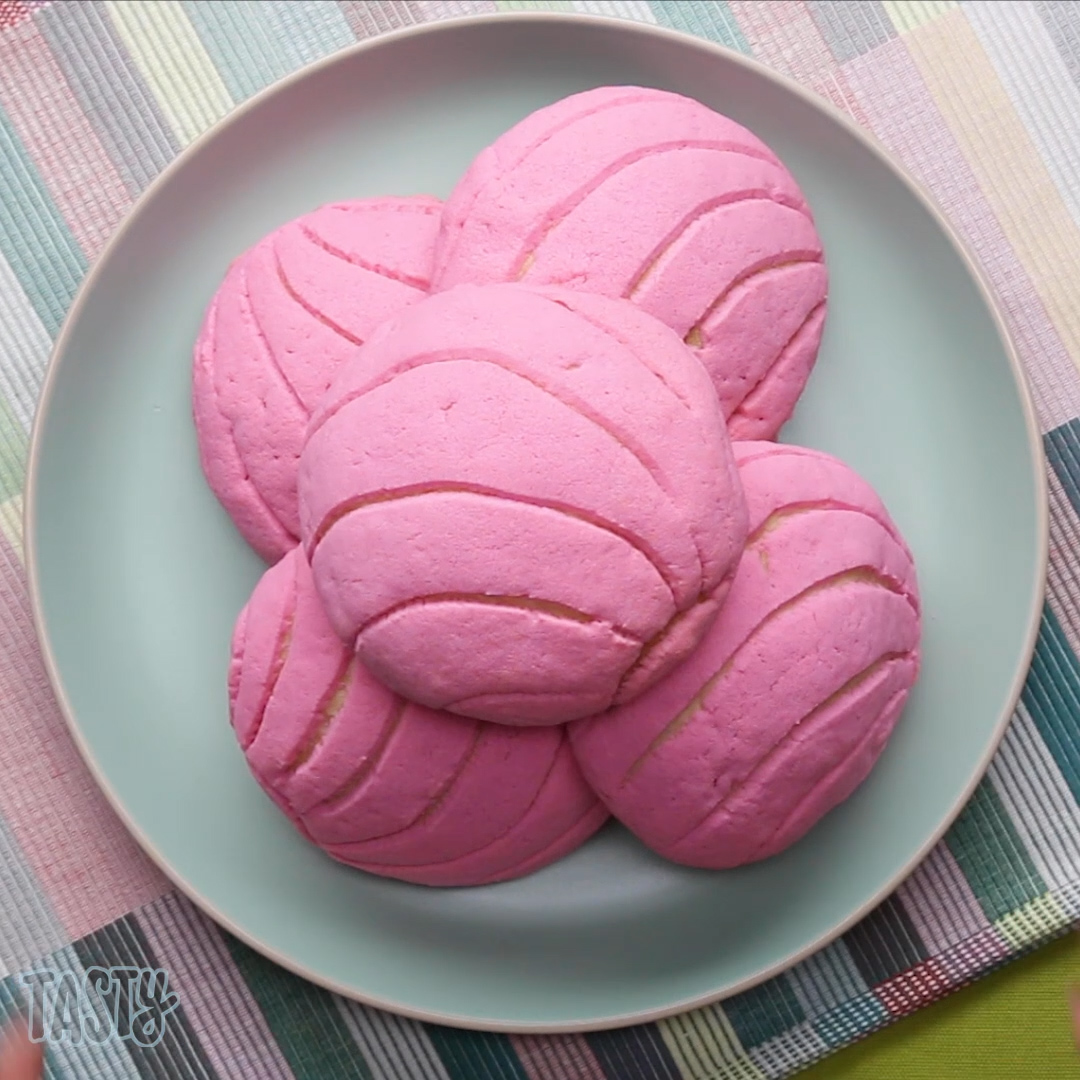 five bright pink circular pastries sit atop a plate 
