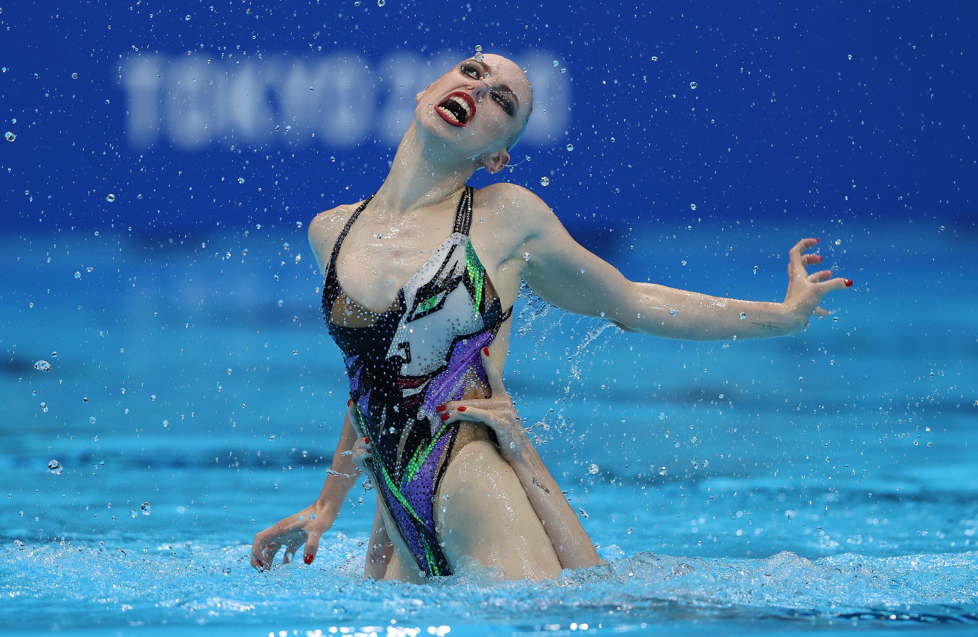 An artistic swimmer jumps out of the water with an intense facial expression An artistic swimmer jumps out of the water with an intense facial expression