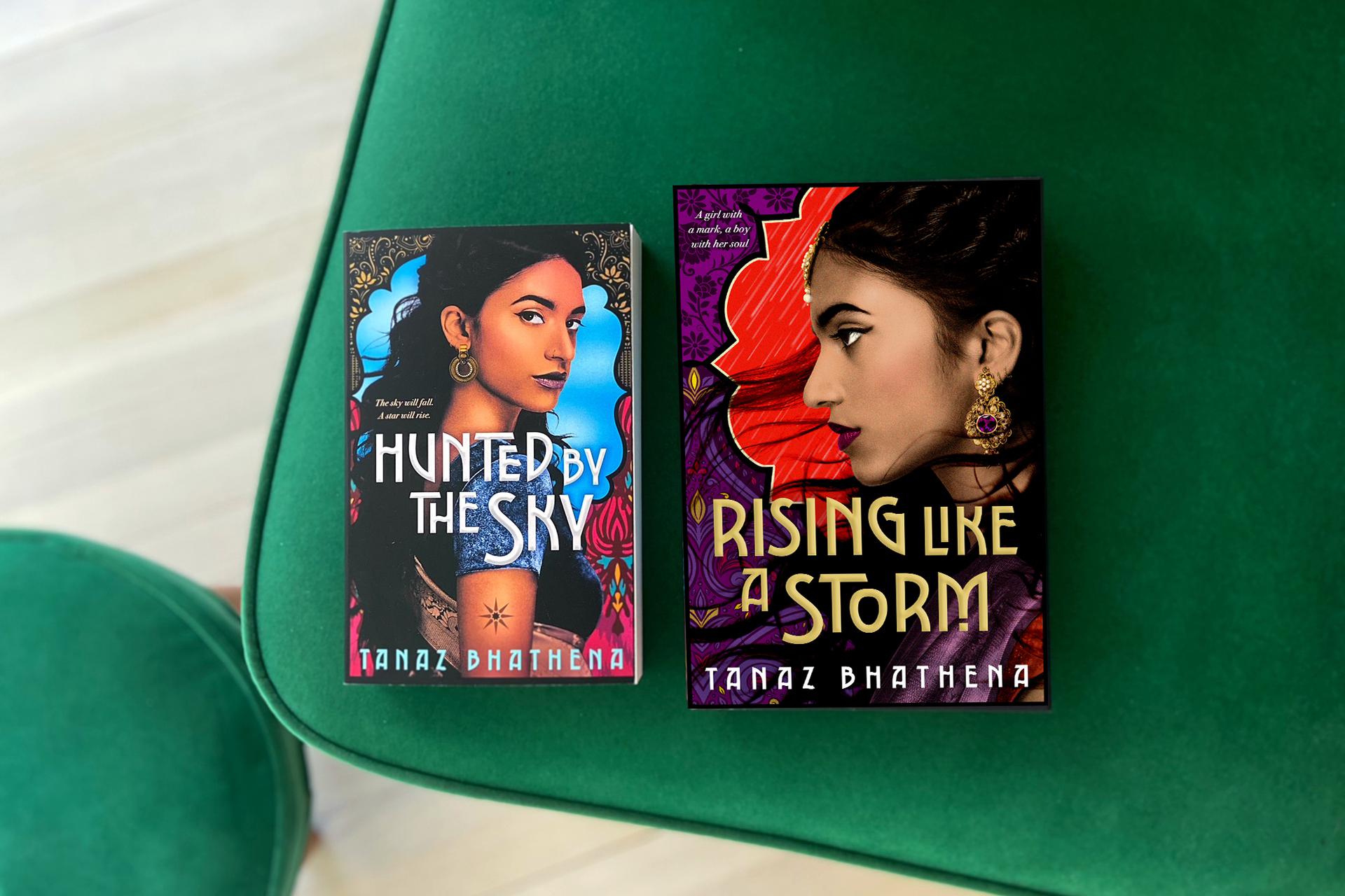 Photo of two books (''Hunted by the Sky'' and ''Rising Like a Storm,'' both by Tanaz Bhathena) on a green cushion 