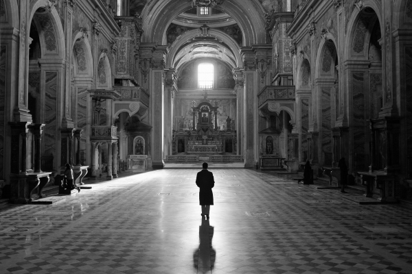 A person walking in a grand hall with intricate detailing.