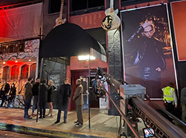 A group of people standing outside of a venue on a TV set.
