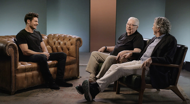 Three people on couches smiling and having a conversation.