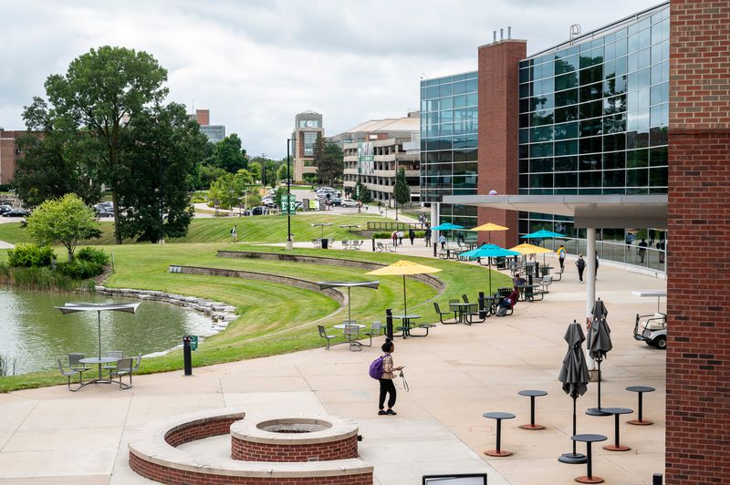 A student with a purple backpack walks alone through a mostly empty courtyard outside the Eastern Michigan University student center 