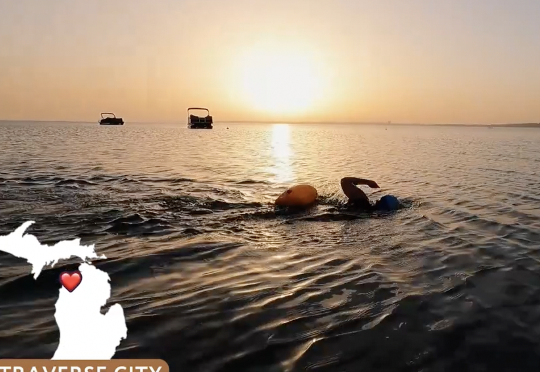 a swimmer does freestyle in a wetsuit at sunrise in grand traverse bay