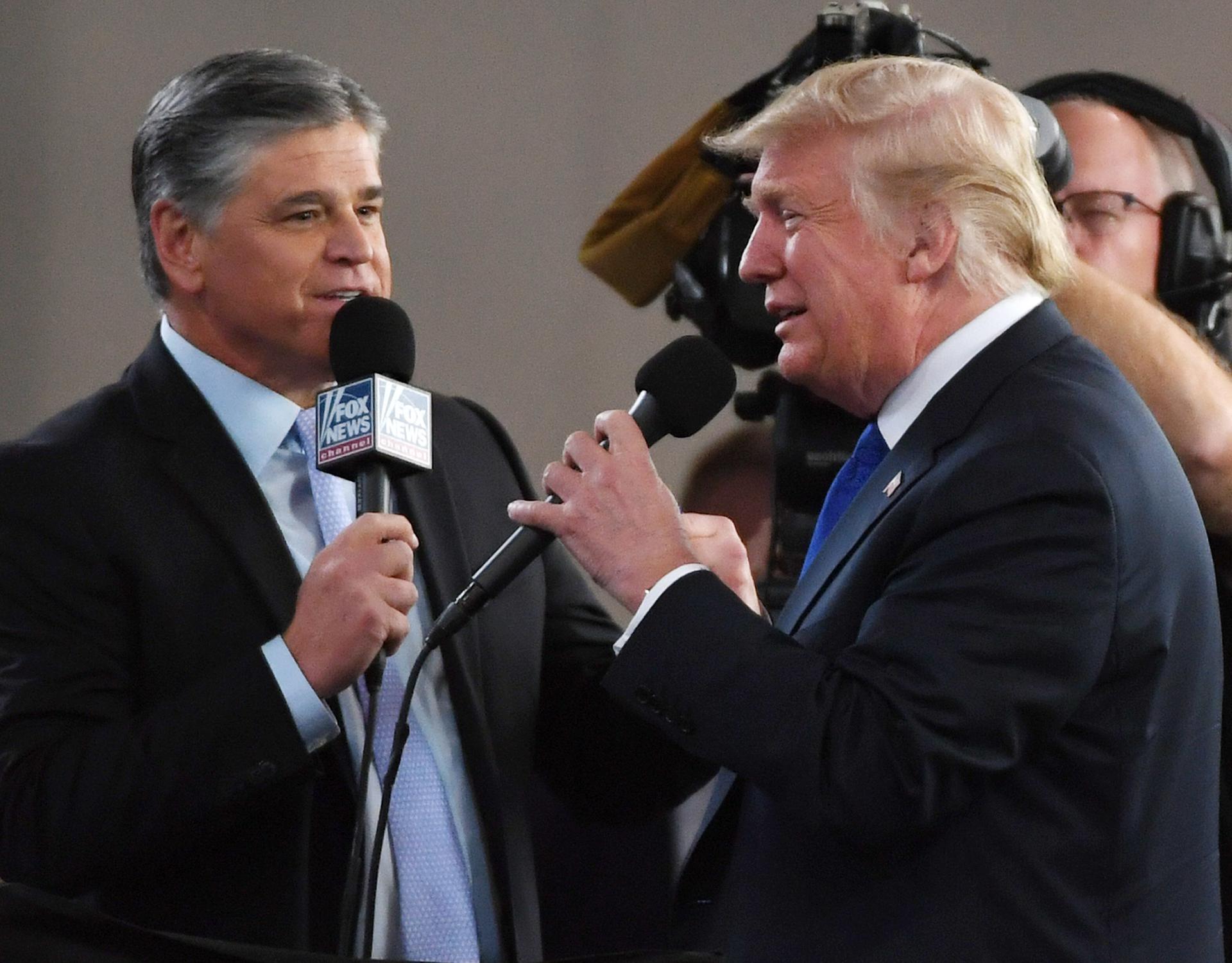 Sean Hannity, left, holds Fox News microphone and interviews Donald Trump, right, in 2018.
