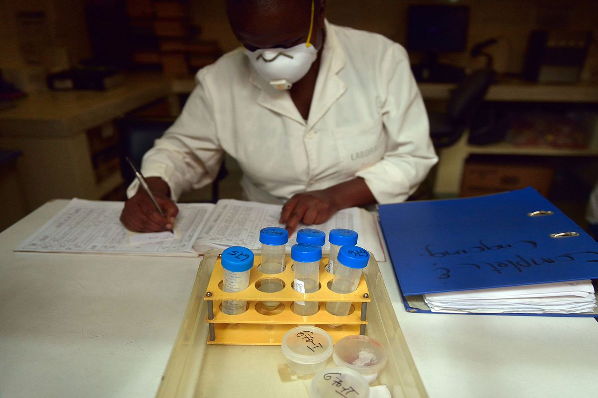 A laboratory technician logs samples in vials from tuberculosis patients to be tested for TB strains.
