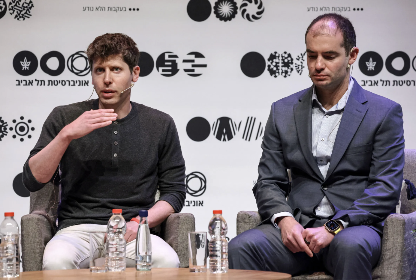 Sam Altman is seen in profile against a dark background with a bright light overhead.