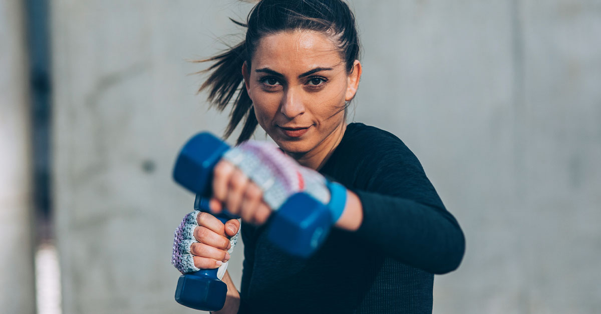 woman holding dumbbell doing a punching workout