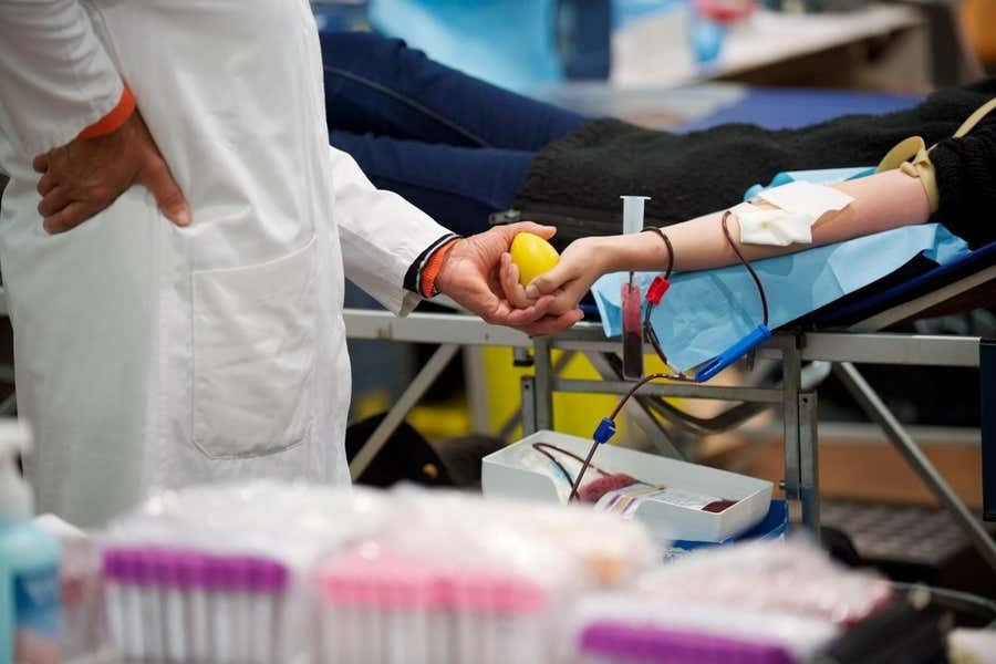 Image of someone getting their blood drawn as a doctor stands by