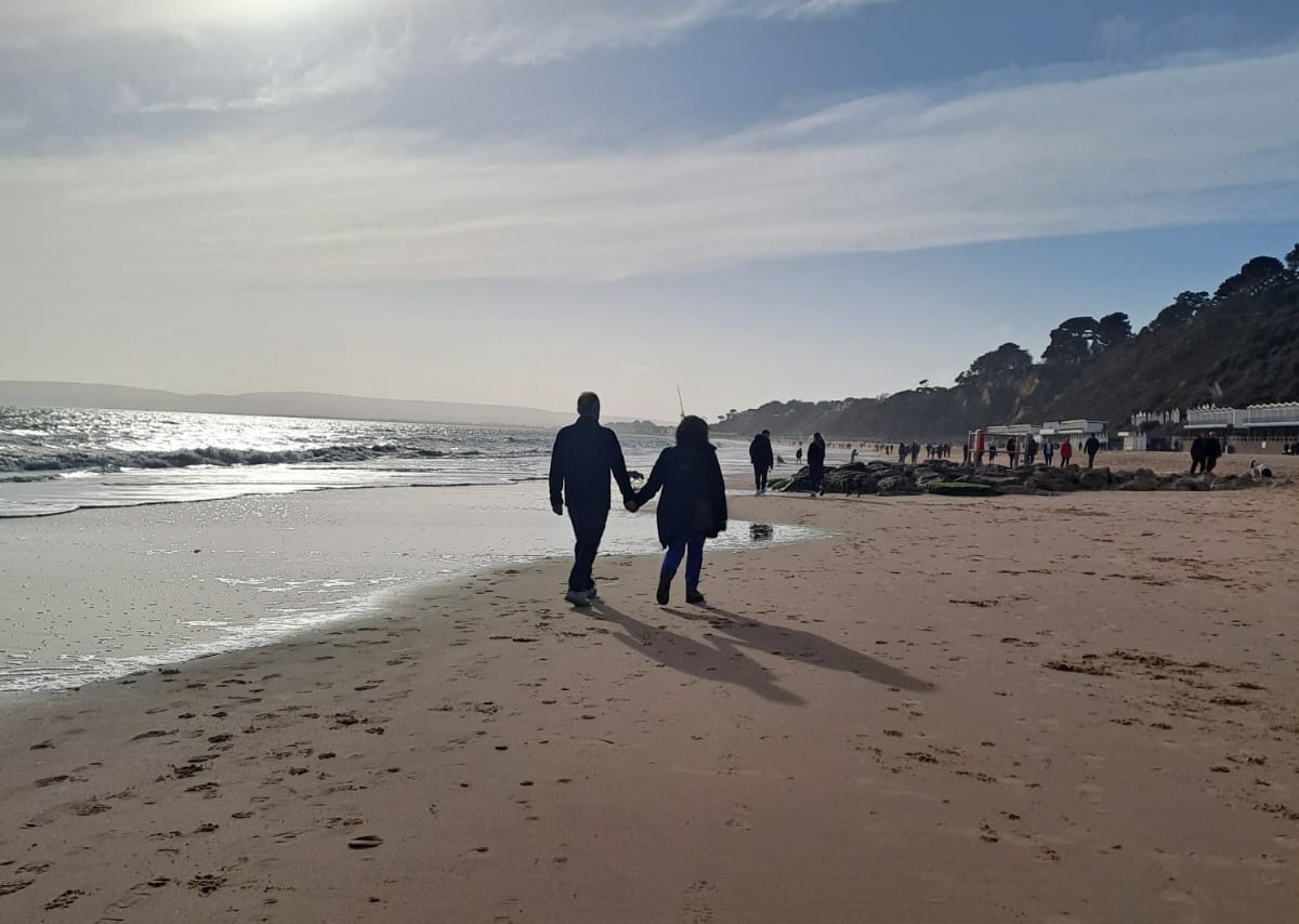 Two people walk on a beach