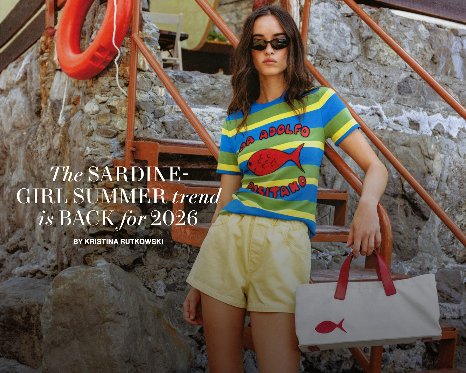 Model on a beach in a staud outfit holding a staud bag