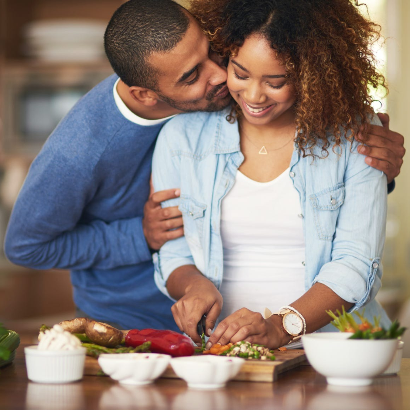 Couple embracing and smiling while making dinner
