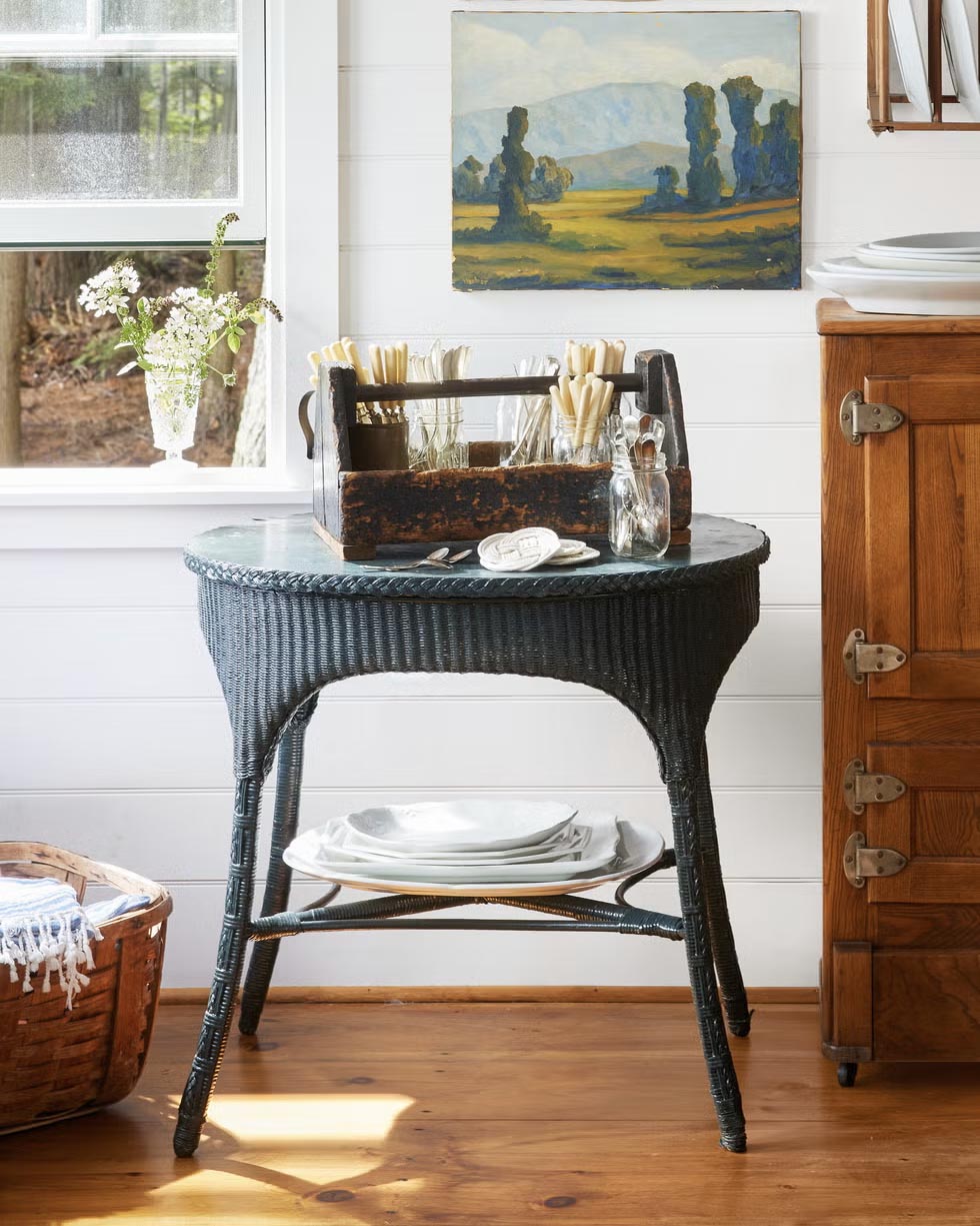 scene with various antiques including wicker side table, wooden caddy, paintings