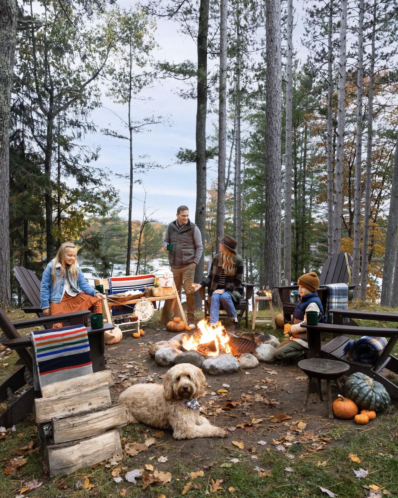 family gathered around lakeside campfire on a fall day