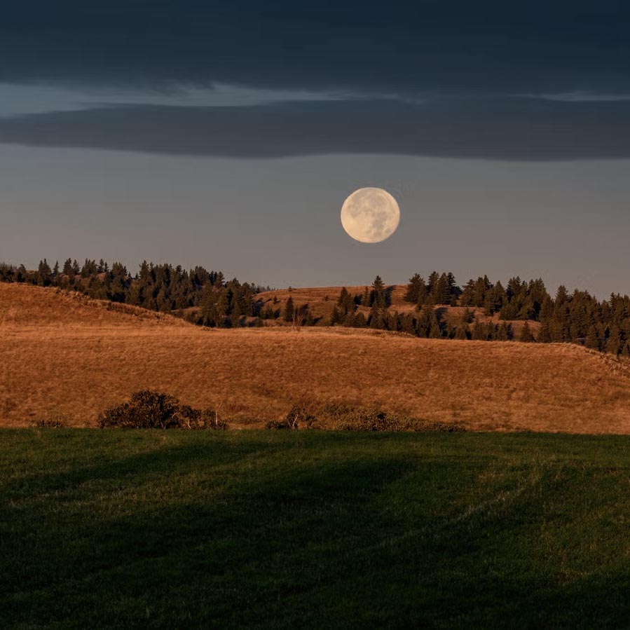 full moon shines over rolling countryside