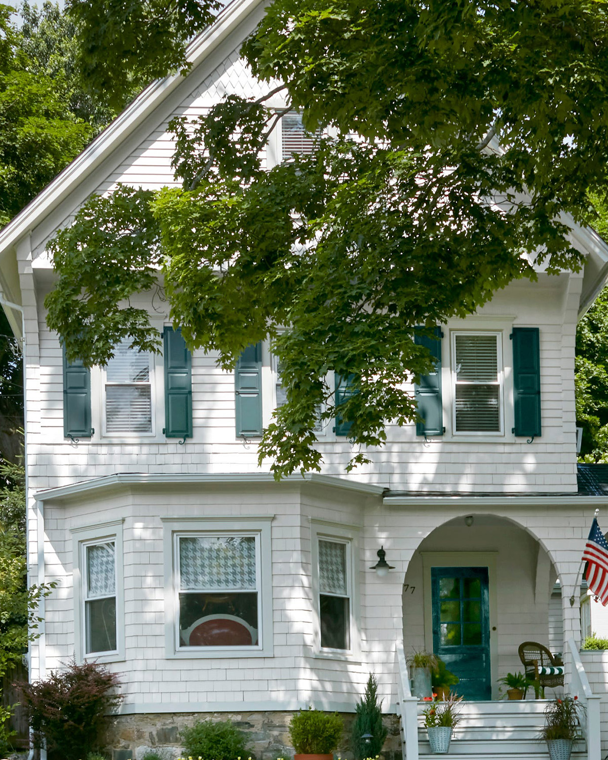 two-story white Victorian house with tree in front