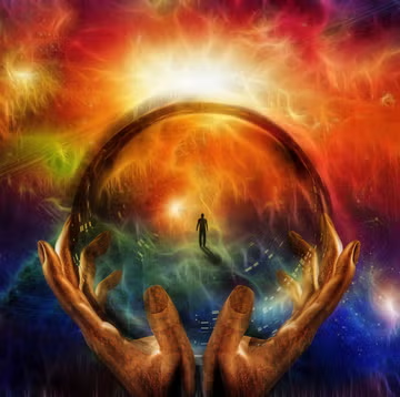hands hold glass sphere with image of man in the center
