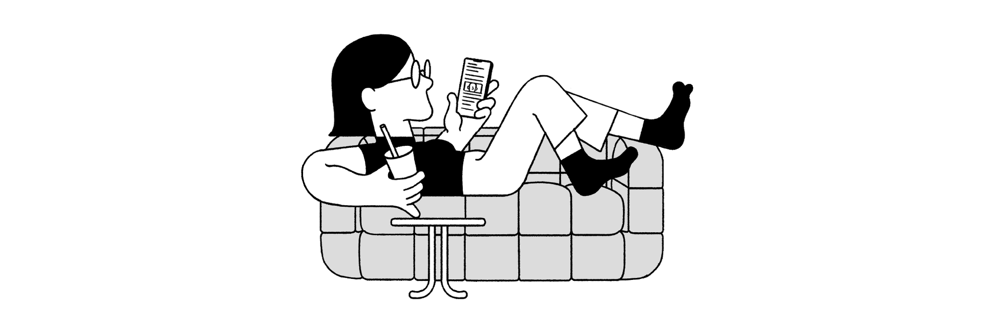 A person reclining on the couch, shoes off, reading their phone with a beverage in hand. 
