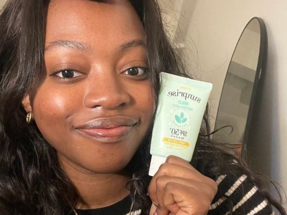 Person holding sunscreen for dark skin