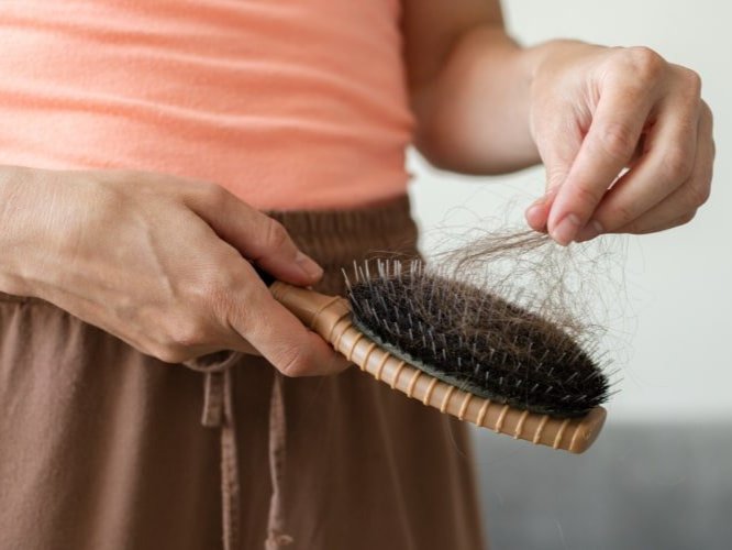 Person pulling hair from hairbrush