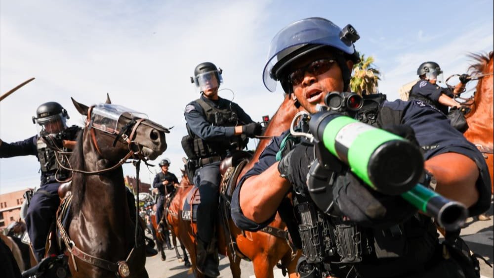 olice holding weapons face off with protestors during a 