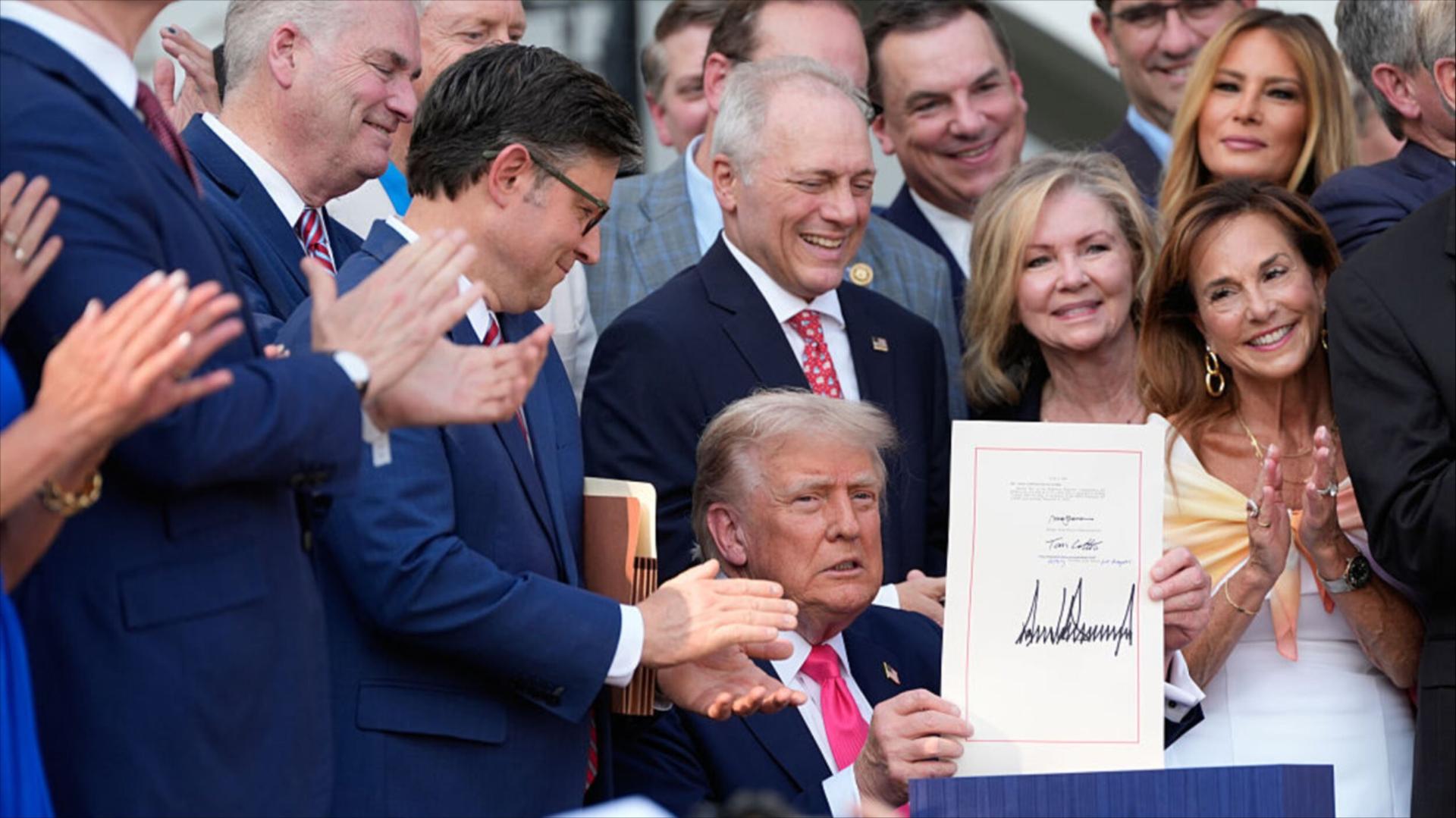 Congressional Republicans and Melania Trump surround President Donald Trump as he signs the One Big Beautiful Bill Act.