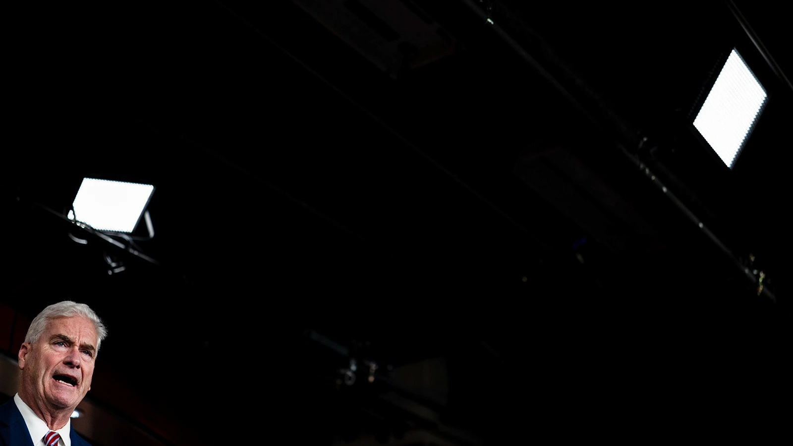 Tom Emmer's face is visible in the bottom left corner of the photo. The rest is black, save for a few square lights.