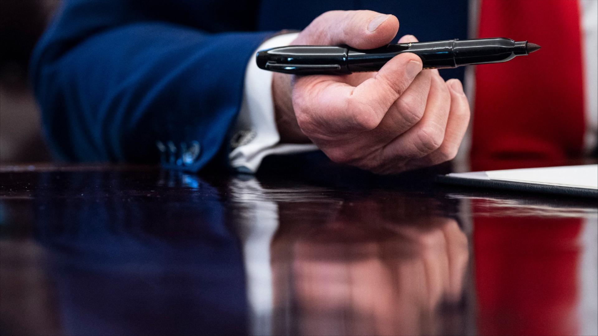 A close up of President Donald Trump's hand holding a pen