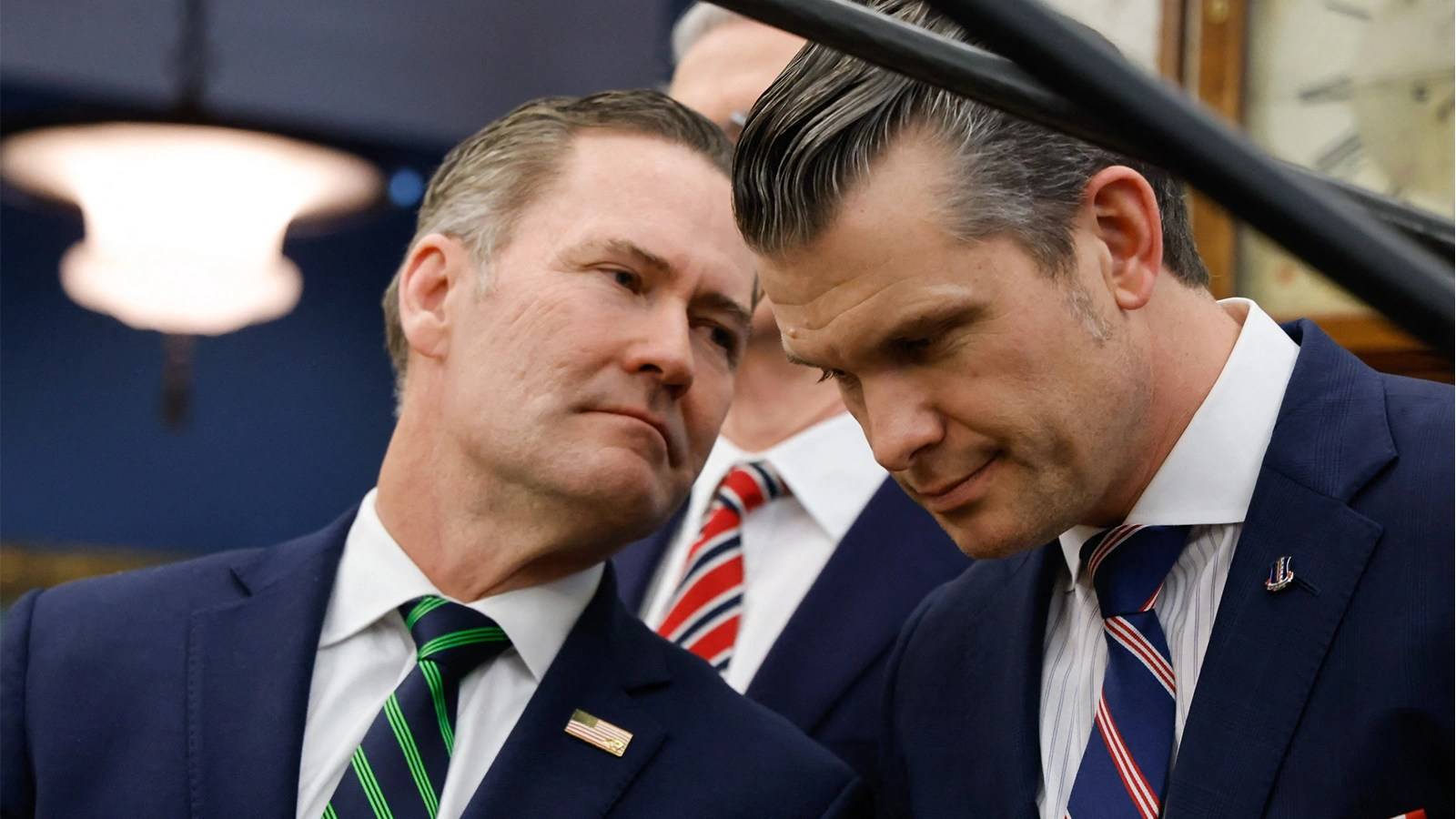 Pete Hegseth, right, leans toward Mike Waltz as they speak.