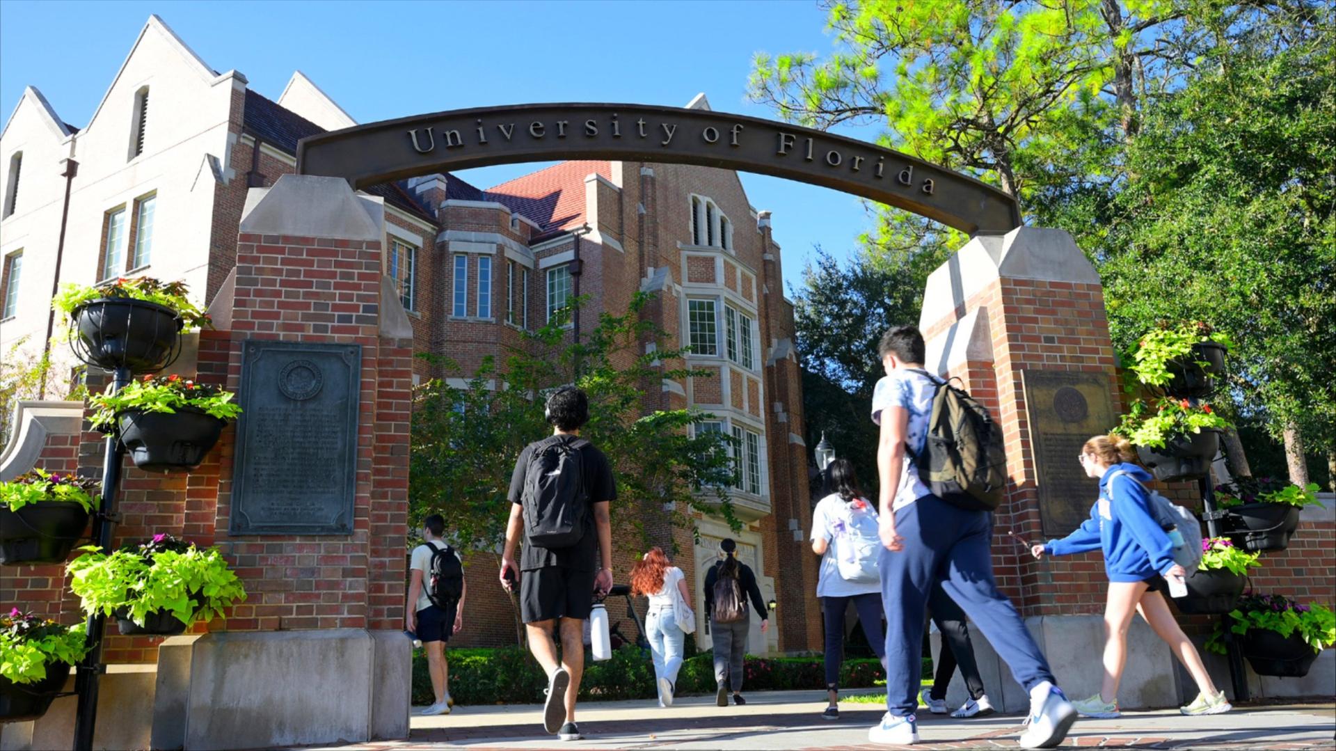 Students walk under the arch of University of Florida entrance