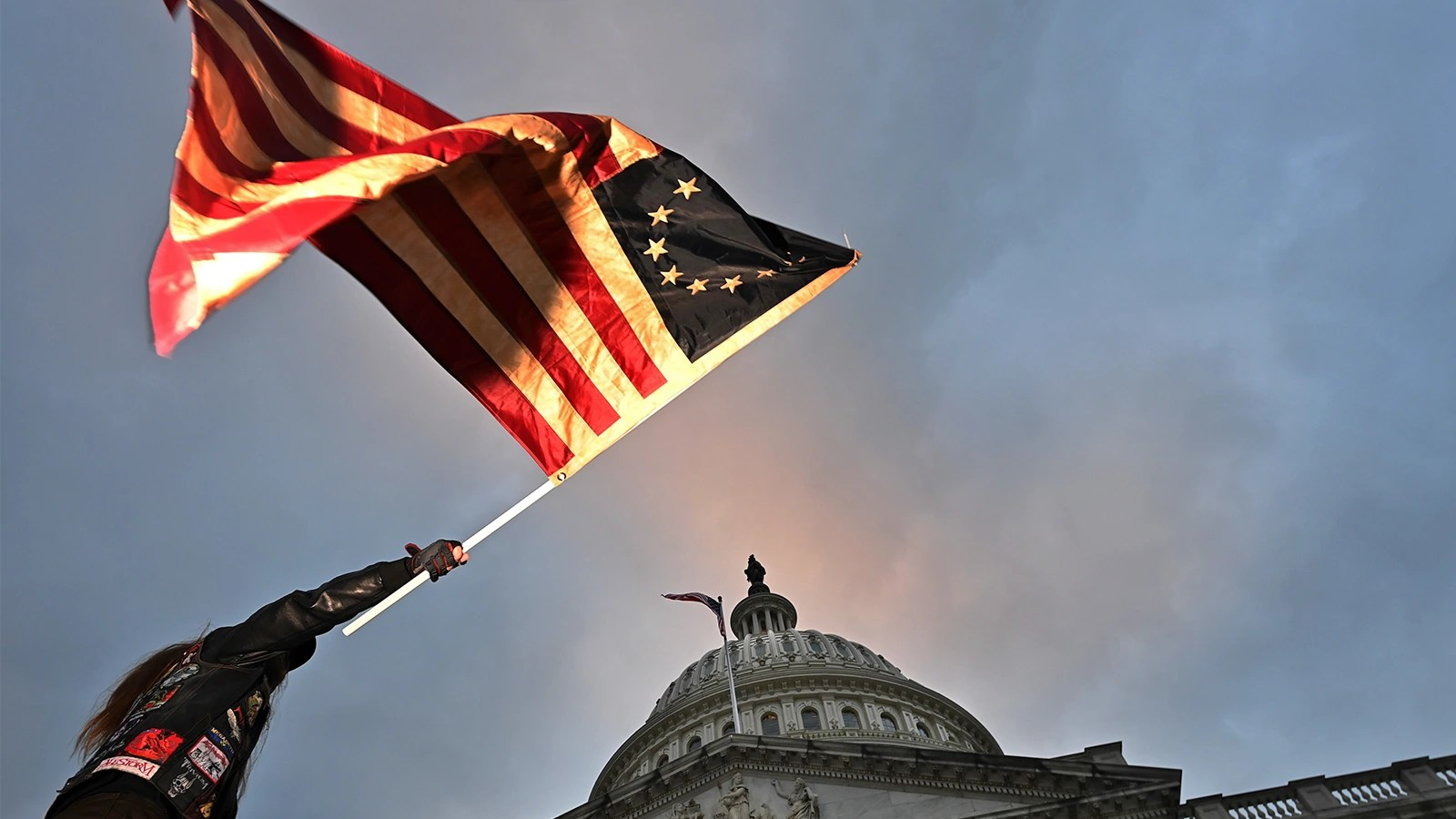 A photo of someone raising the American flag above the U.S. Capitol