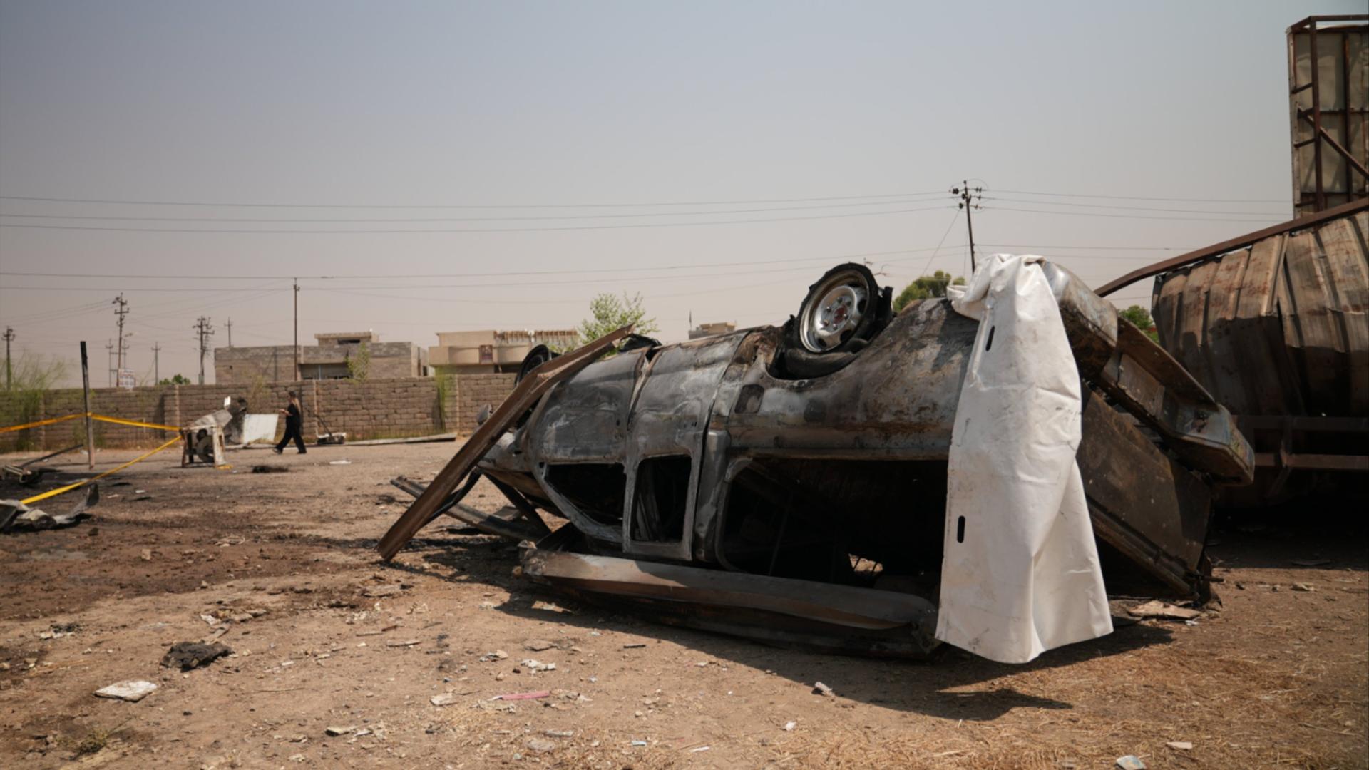 A car is upturned and lying in the desert.