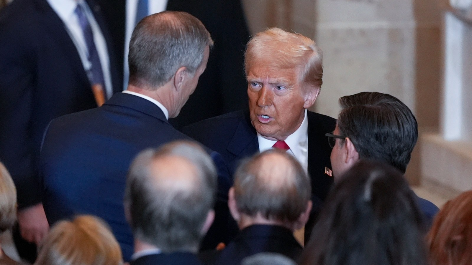 Donald Trump, center, speaks to John Thune, left, who has his back toward the camera. Mike Johnson, also with his back toward the camera, stands on the right. 