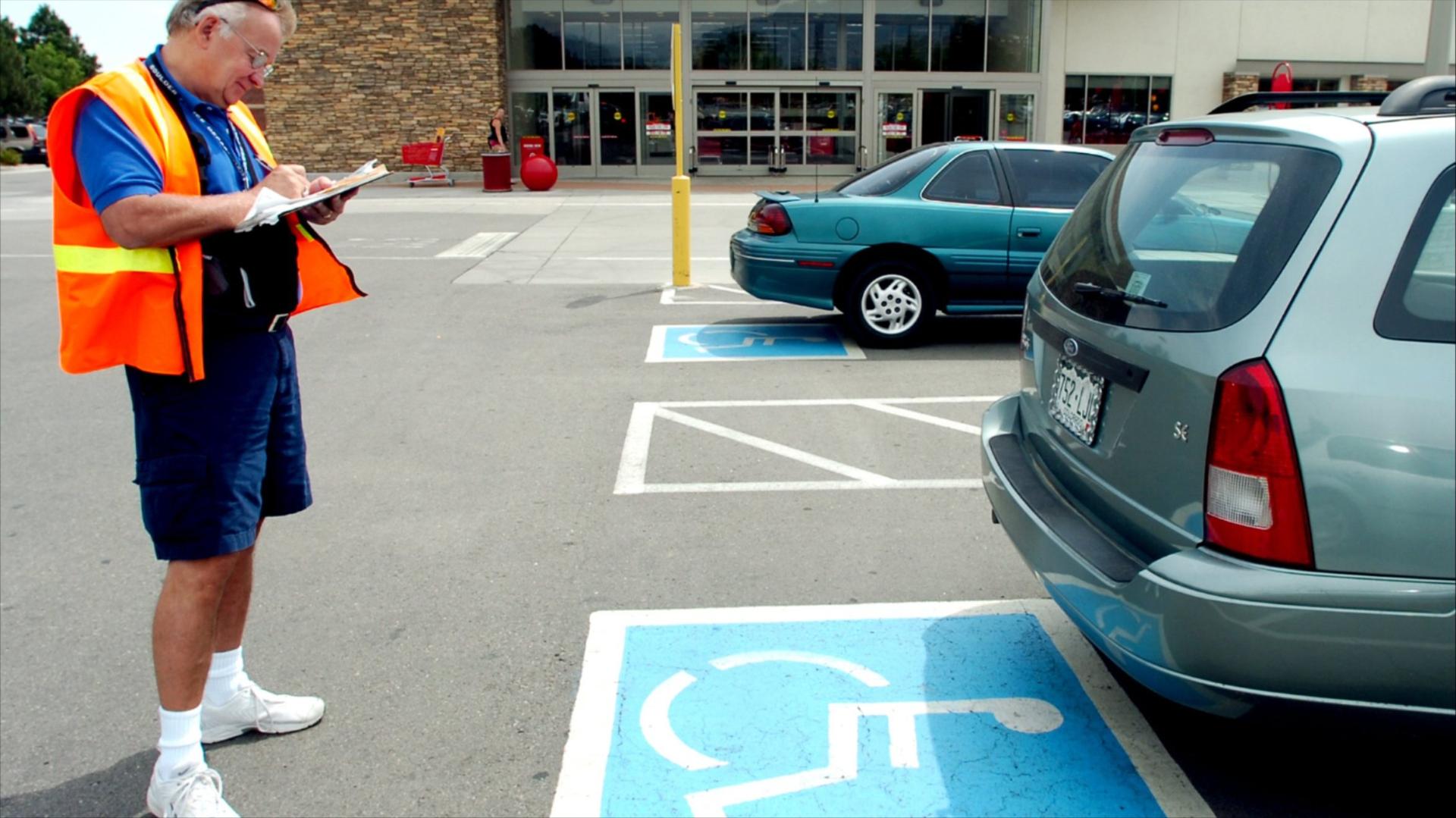 Volunteer handicapped parking enforcement officer Russ Ricker writes a parking ticket for a car parked without a handicapped plate or place card at a store parking lot on July 6, 2006, in Boulder, CO
