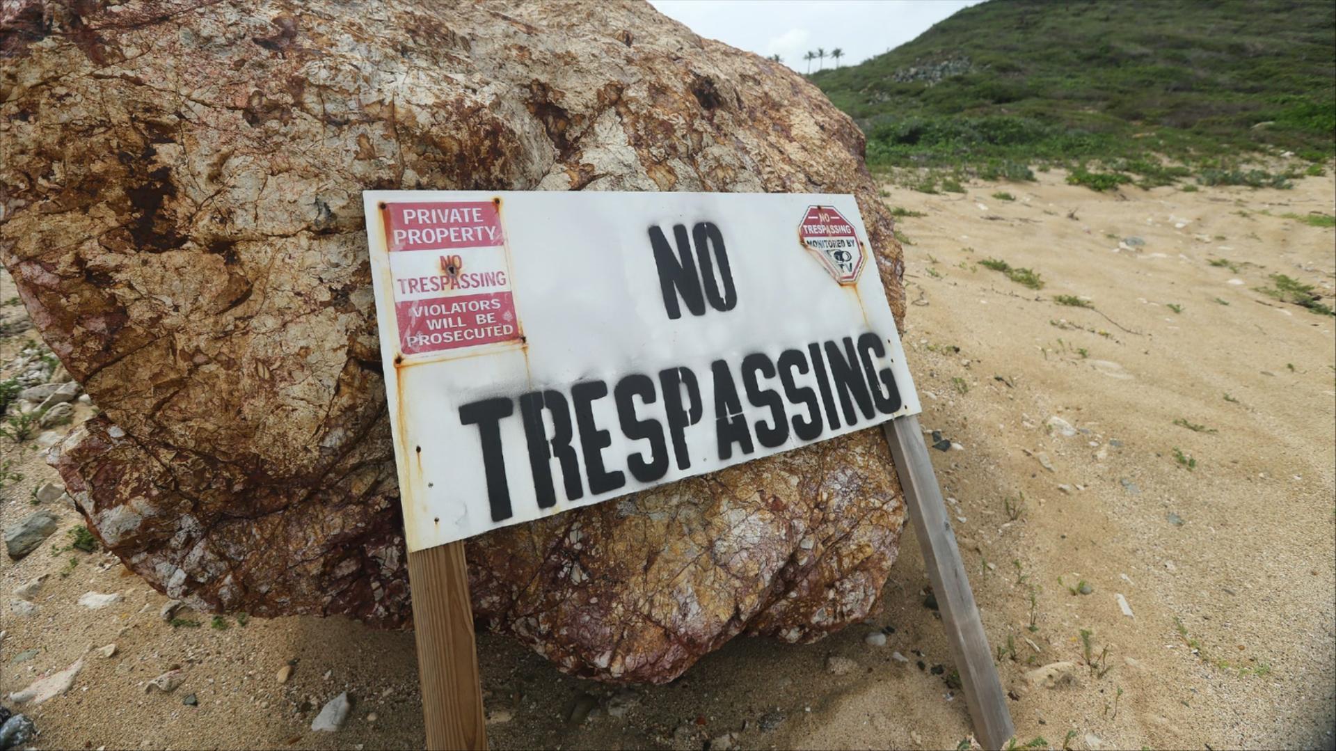 Sign leaning against a small boulder