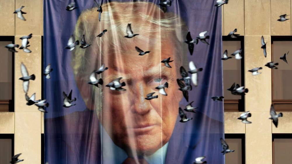 Birds fly past a giant banner with the image of President Donald Trump on Jan. 05, 2026 hanging on the outside of the U.S. Department of Labor