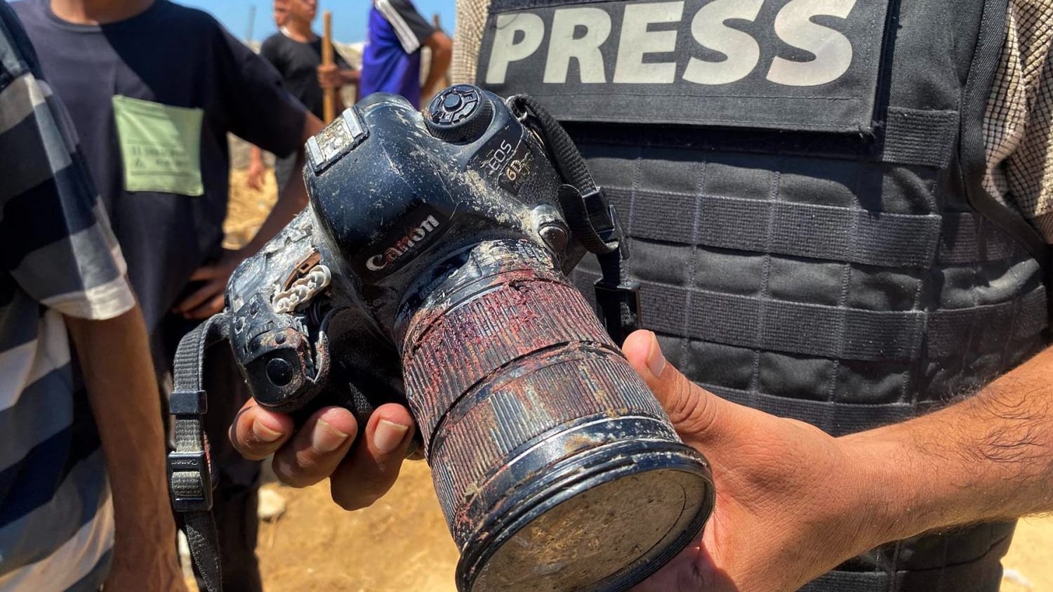 A journalist at the funeral of Palestinian photojournalist Mariam Dagga holds her blood-covered camera, recovered after she was killed Monday in an Israeli strike on Nasser Hospital in the southern Gaza Strip