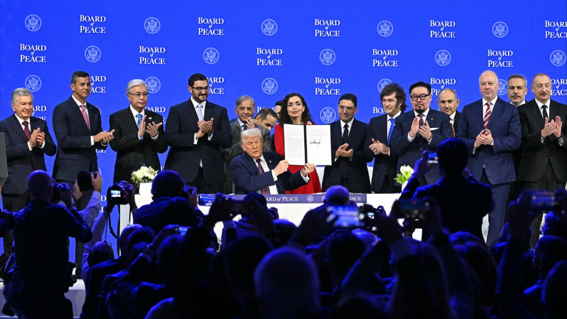 Presidents, prime ministers and other global leaders surround Donald Trump as he holds a signed charter