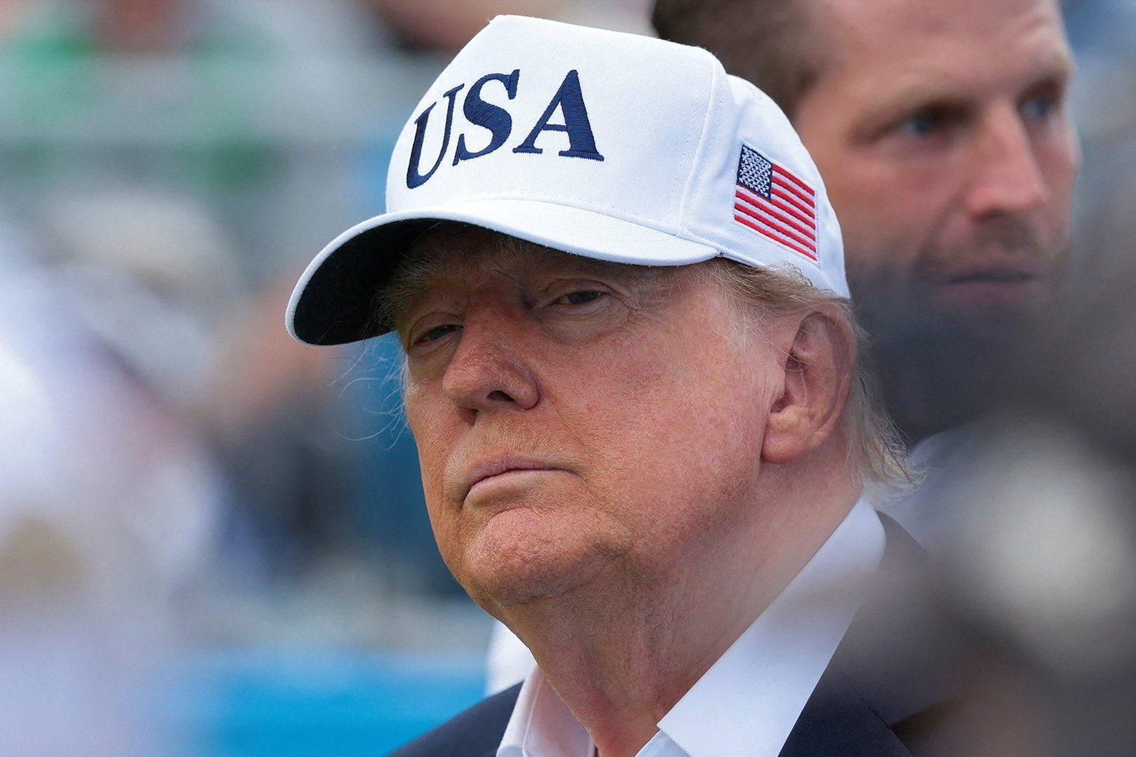 Donald Trump wears a USA hat as son Eric Trump stands behind him