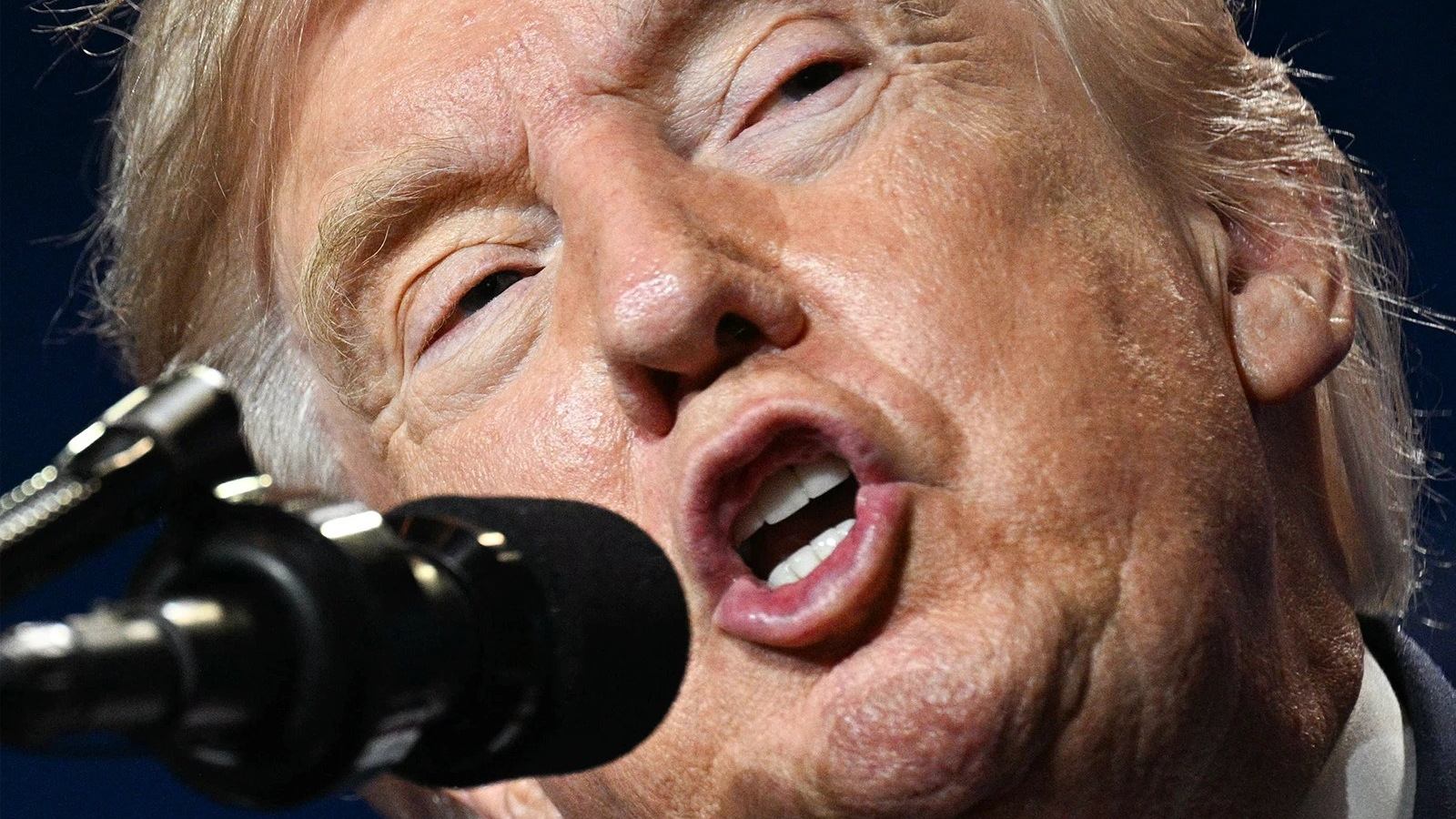 Donald Trump, seen at an extreme close up, speaks into a microphone.