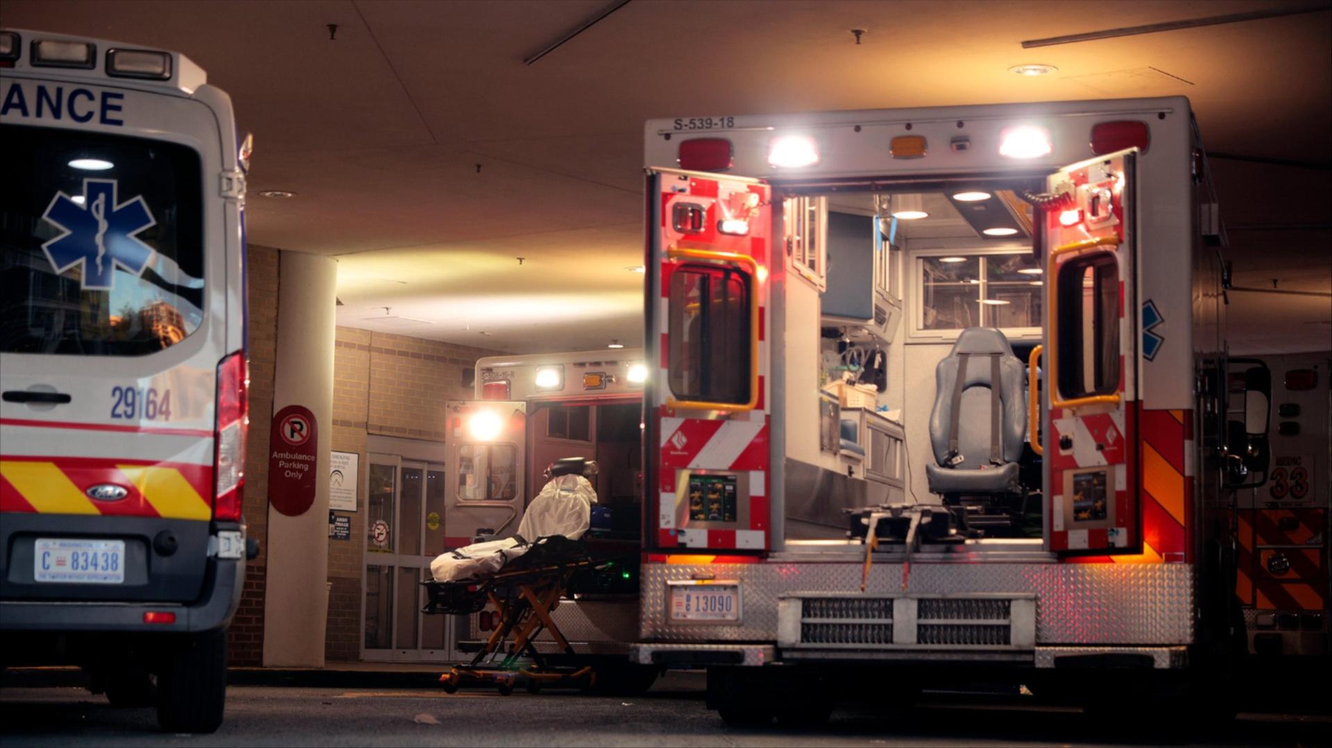 Two ambulances and a gurney in the ambulance bay of a hospital