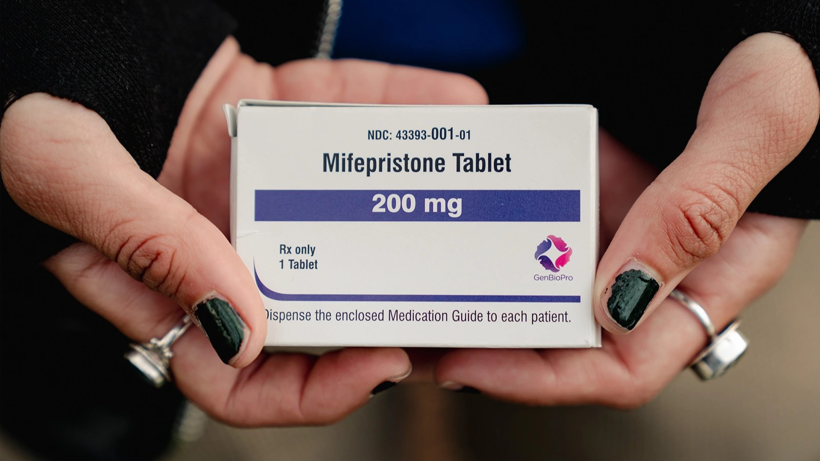 A person's hands hold a box of mifepristone.