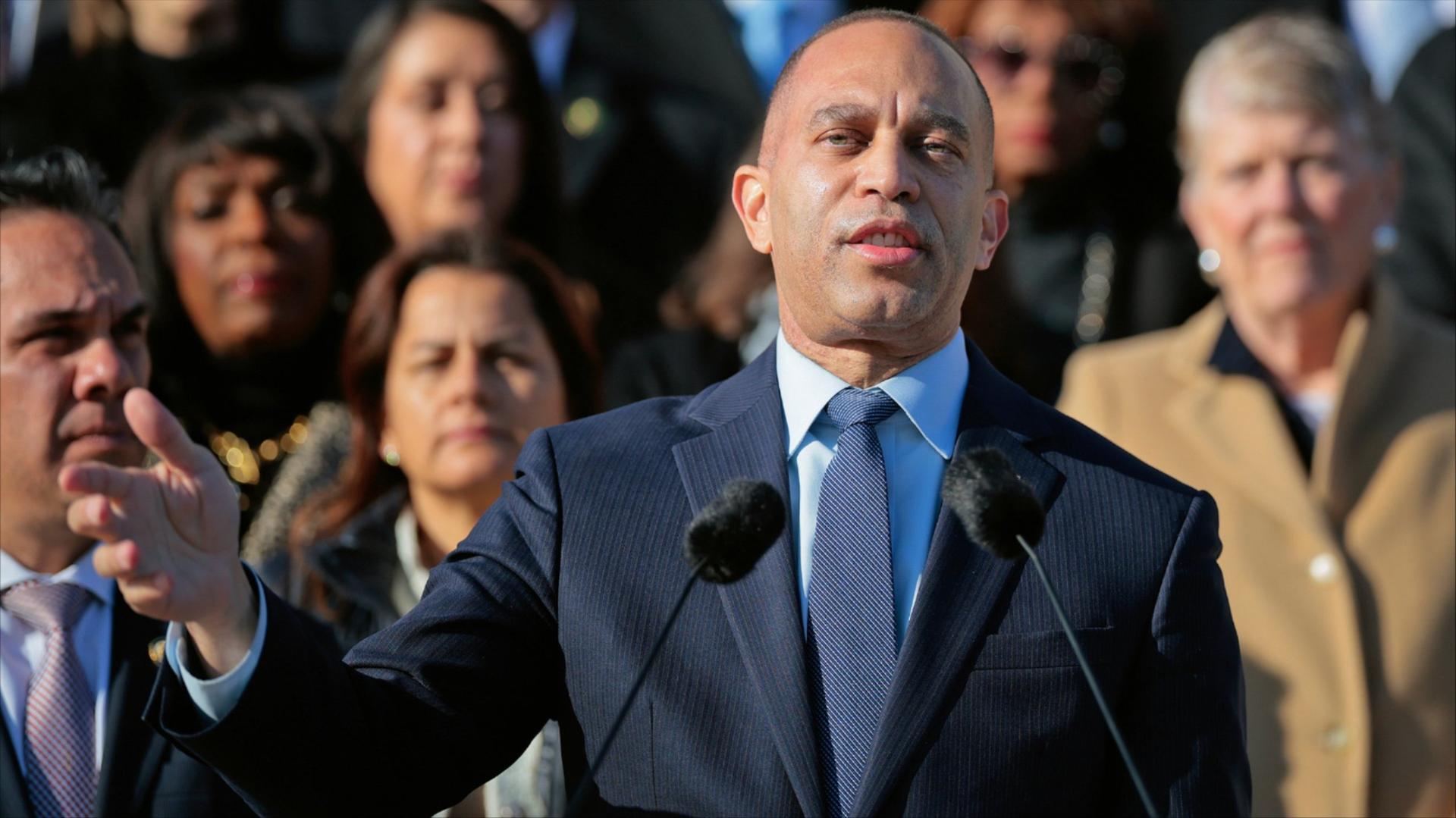Hakeem Jeffries stands at a podium in front of a crowd of other Democratic leaders