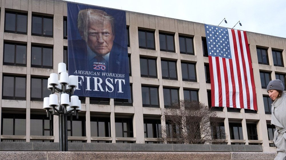 A person walks by a banner depicting President Donald Trump on the facade of the Labor Department building near the Capitol ahead of Trump's State of the Union speech on Feb. 24, 2026.