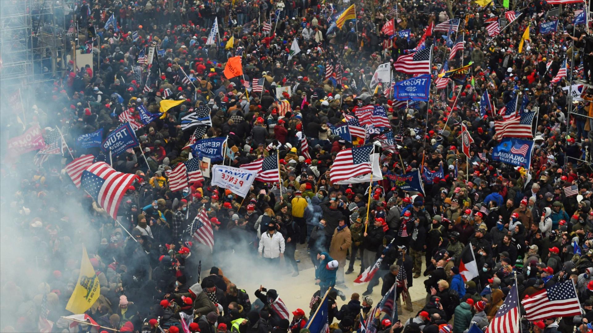  A crowd of people, many carrying Trump flags and American flags