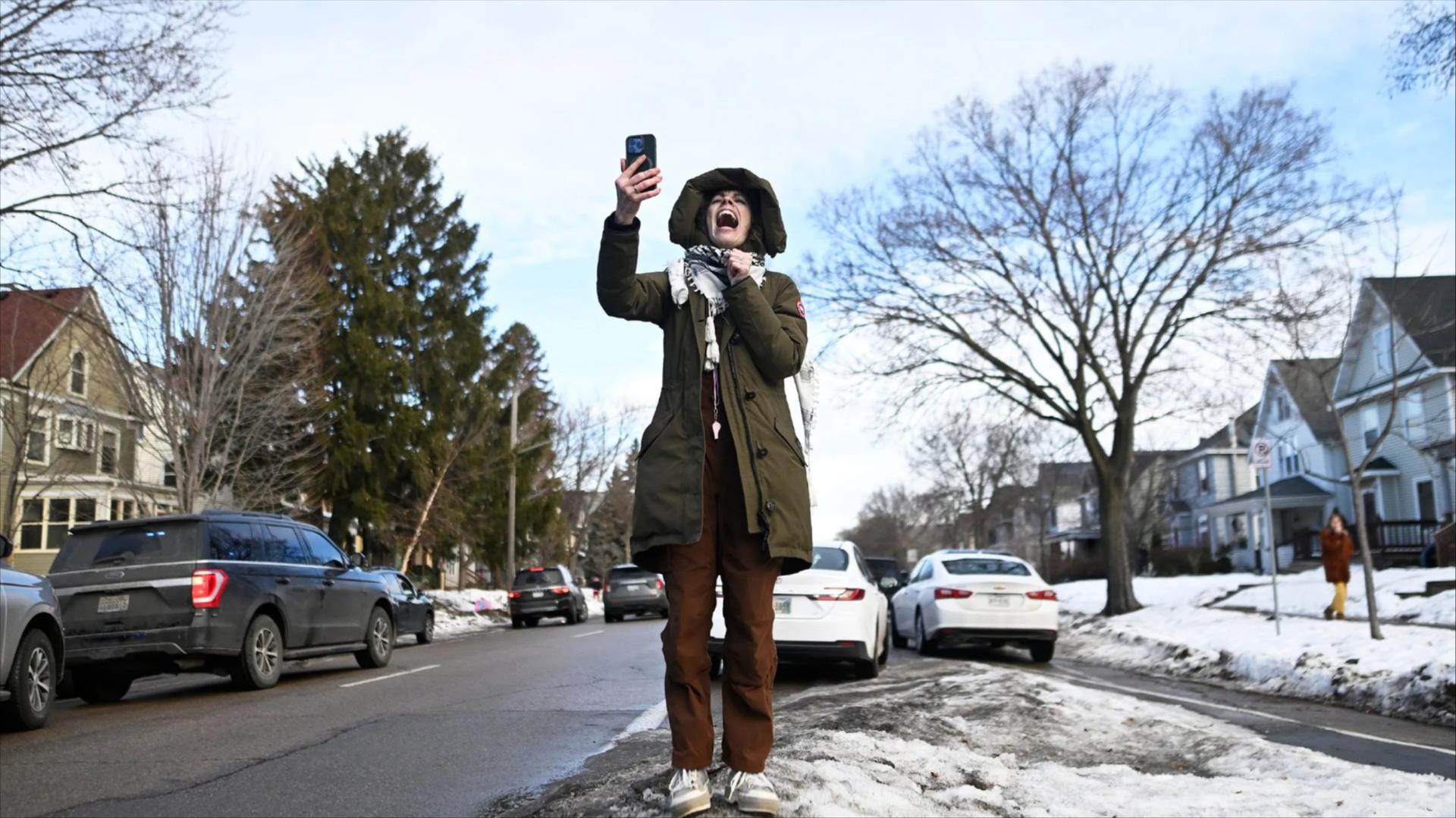 A person yells while holding up a cell phone 