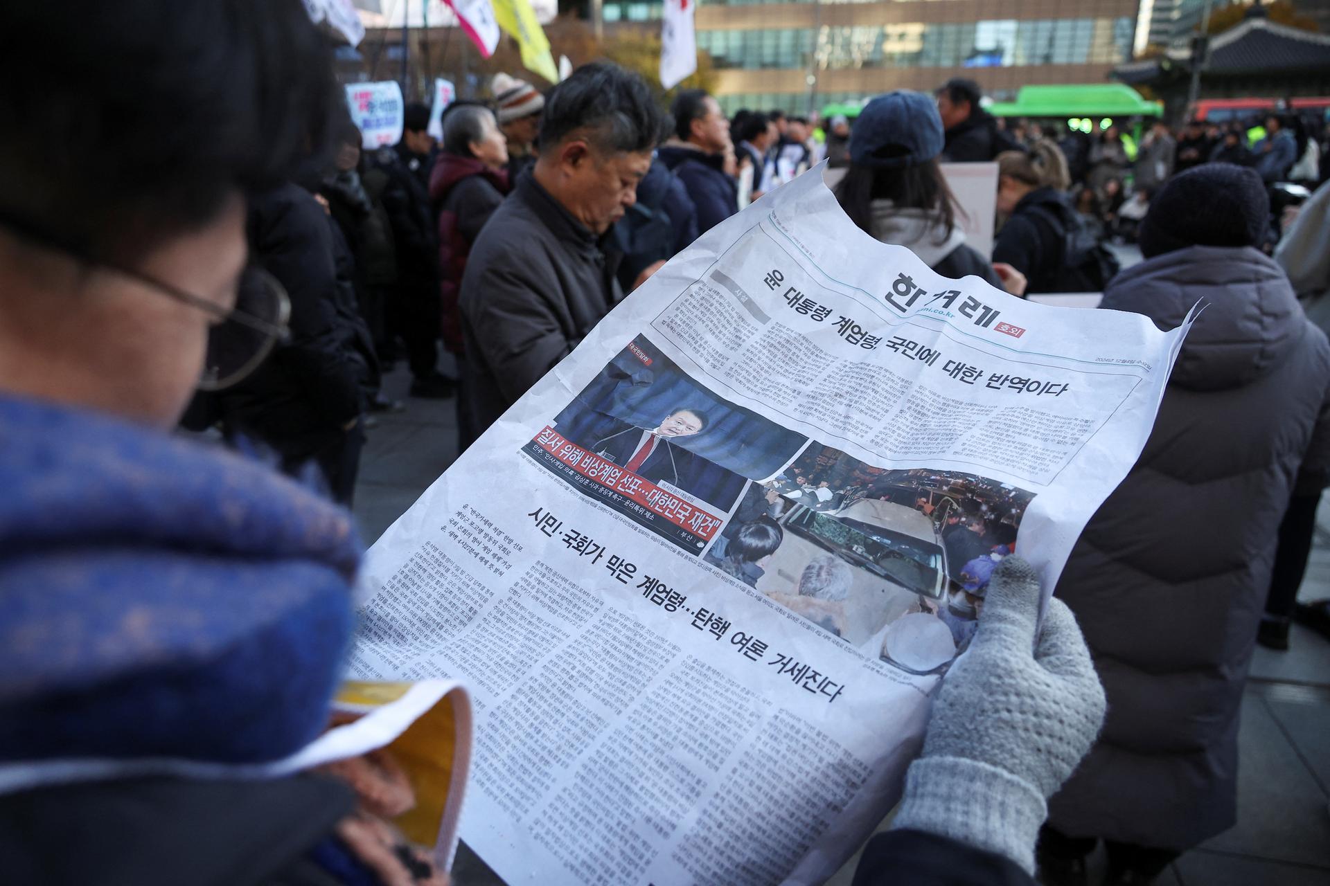 Reading a newspaper during a rally against martial law, Seoul, South Korea, December 2024