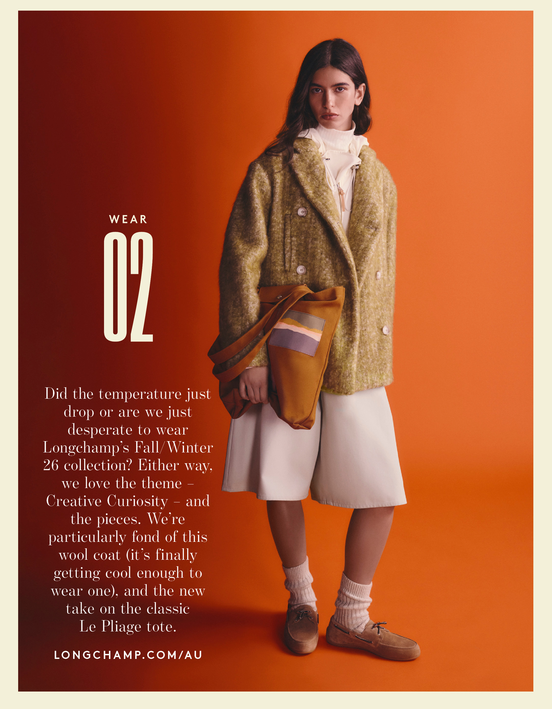 Model in green wool coat, cream shorts, cream socks and deck shoes on an orange background