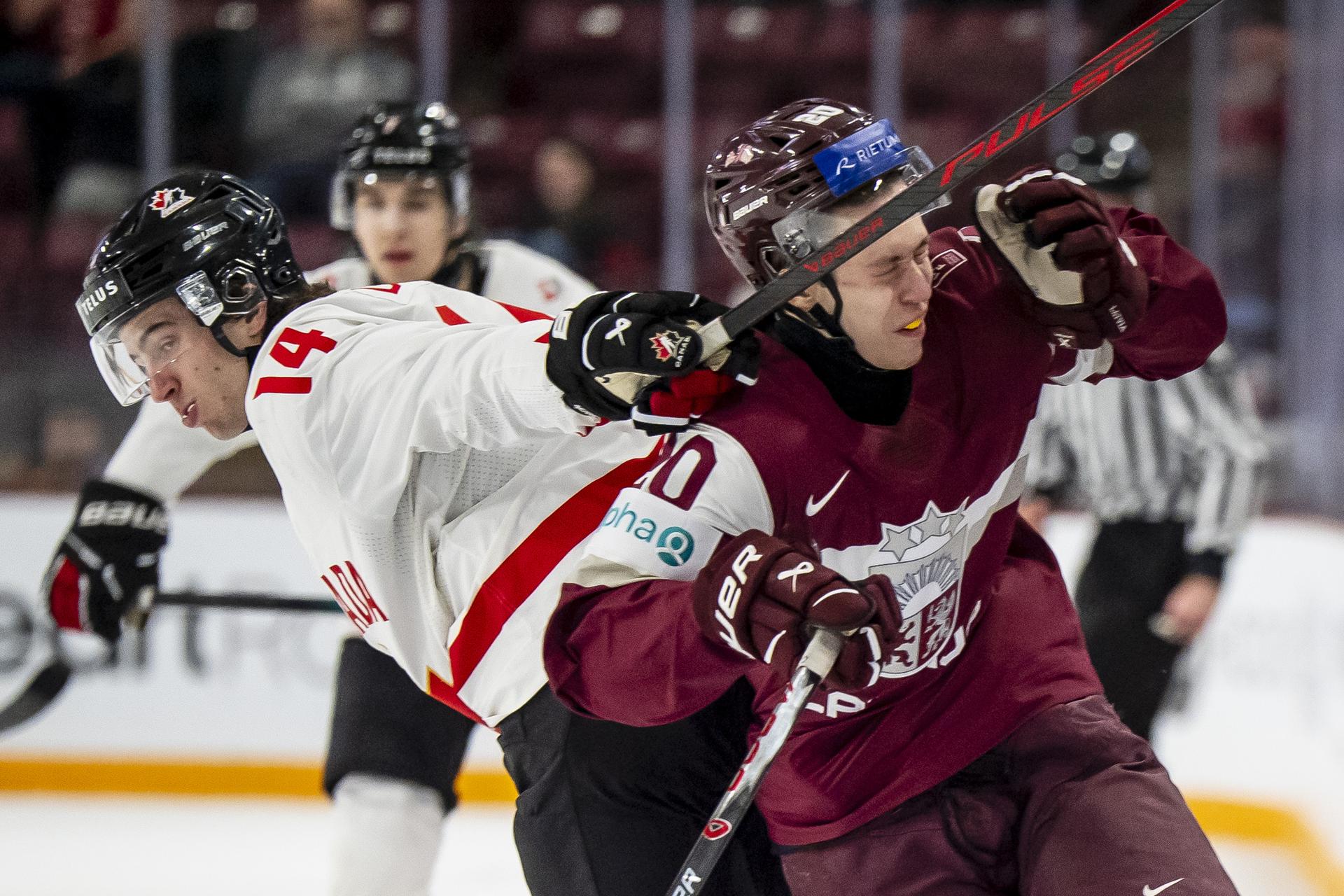 Canadian Ben Danford smacks Latvia's Kristians Utnans in the head with his stick during a game at the world junior hockey championship.